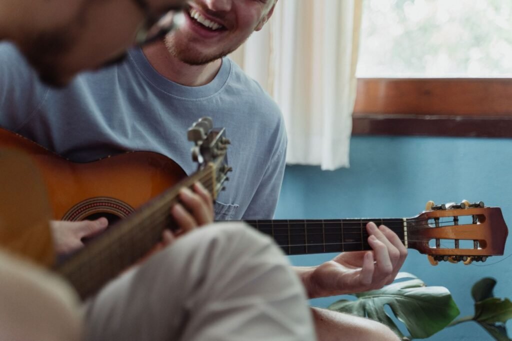 Two adults joyfully playing acoustic guitars indoors, creating a fun musical atmosphere.